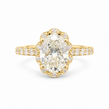 A yellow gold ring featuring a large oval-cut diamond center stone surrounded by a decorative halo of smaller diamonds, with a slim diamond-set band, shown on a plain white background.