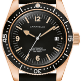 A Caravelle automatic dive watch with a black dial, black rubber strap, and a rose gold-tone case with a black rotating bezel.