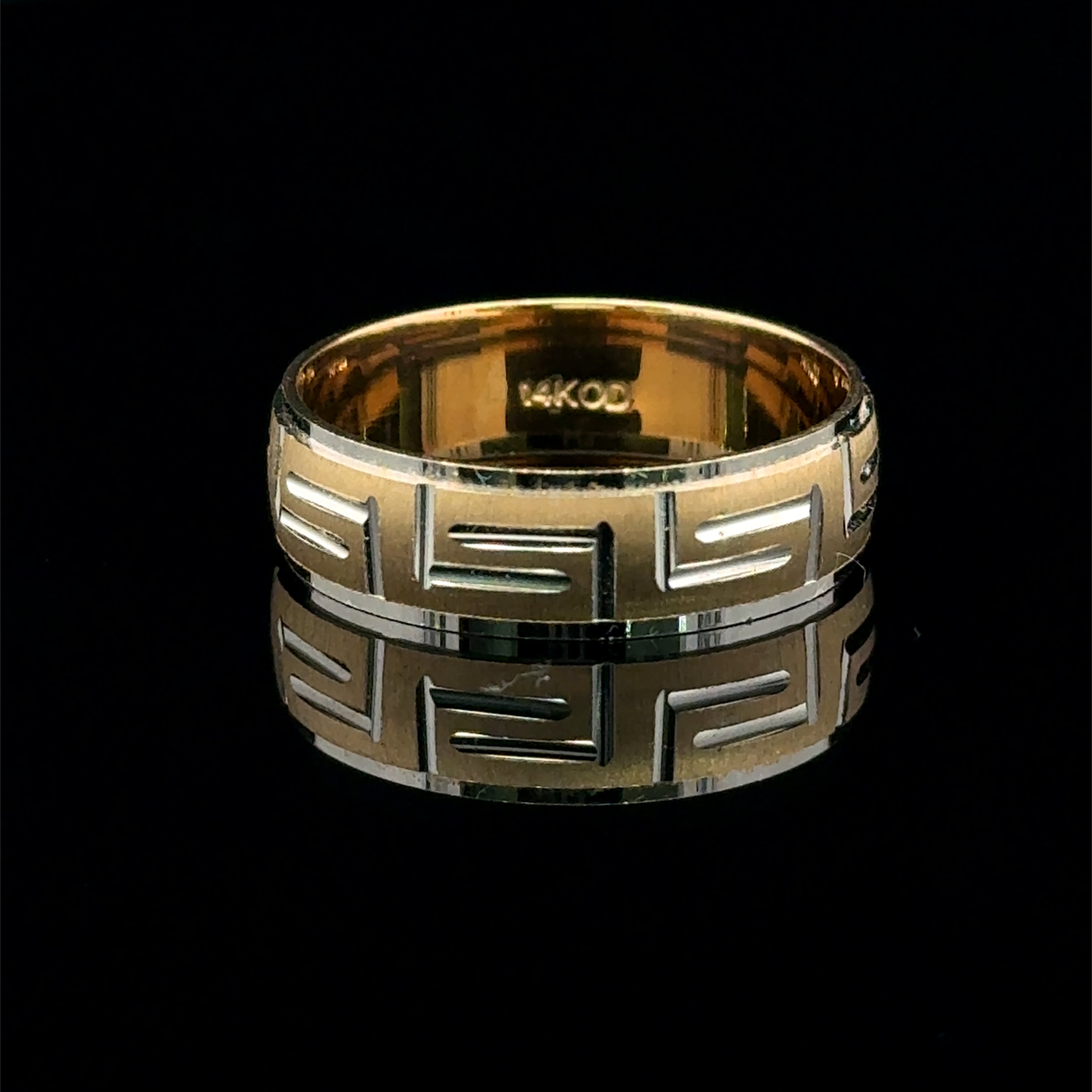 Two-tone men’s gold wedding band with a white-gold Greek key pattern and brushed yellow-gold center.