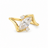 A yellow gold ring featuring a marquise-cut clear center gemstone and two small round side gemstones, set on a clean white background.