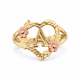 A gold ring featuring a large letter 'A' enclosed in a heart-shaped wreath design, accented with two pink flower motifs on the sides, shown on a clean white background.