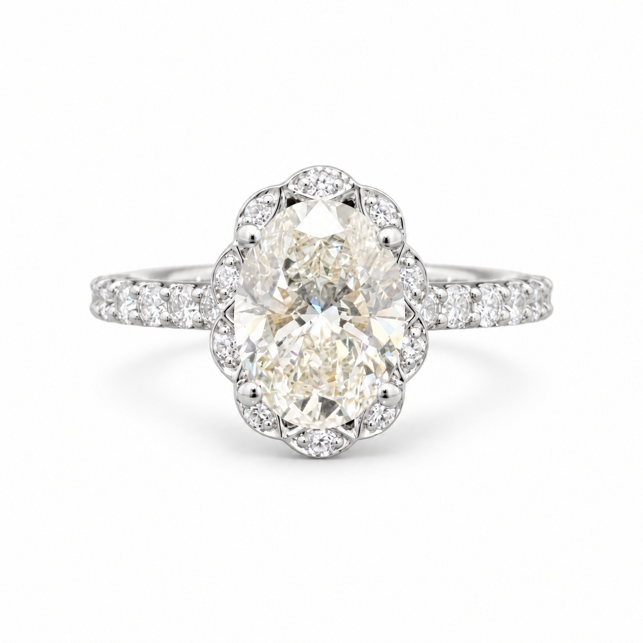 An oval diamond engagement ring with a scalloped halo and a diamond-set band, shown on a clean white background.