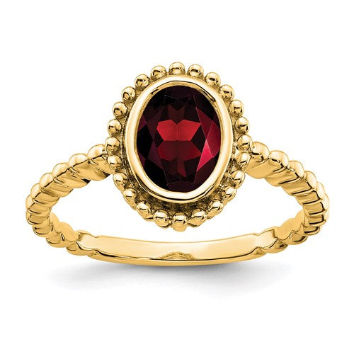 14k oval garnet ring from Solomon Jewelers featuring a vibrant red gemstone in a classic gold setting.