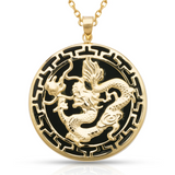 A gold pendant necklace featuring a raised dragon motif over a black circular background with a gold border, suspended from a gold chain on a white background.