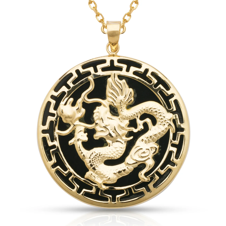A gold pendant necklace featuring a raised dragon motif over a black circular background with a gold border, suspended from a gold chain on a white background.