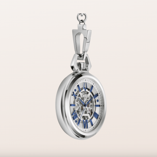 A silver-tone pocket watch with a skeleton dial and blue accents, shown open against a light beige background.