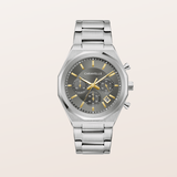 A silver-tone metal chronograph watch with a dark gray dial, yellow accents, and a matching stainless steel link bracelet, shown against a light beige background.