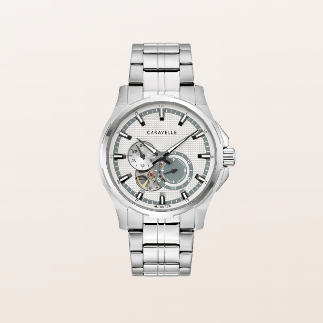 A silver-tone stainless steel wristwatch with a multi-link bracelet, featuring a skeletonized white dial with a visible mechanical movement and a gray subdial, shown against a solid light beige background.