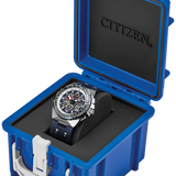 A Citizen watch with a silver-toned case and black dial is displayed inside an open bright blue hard case with a black interior. The brand name CITIZEN is embossed on the inside lid.