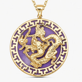 A round gold pendant necklace featuring a raised gold dragon motif over a purple enamel background, with a matching gold Greek key border and chain, shown on a light gray background.