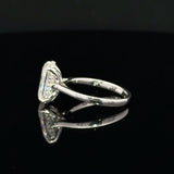 A silver ring with a rectangular pavé diamond setting, shown from a side angle on a reflective black surface.