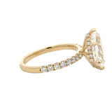 A yellow gold ring featuring a large marquise-cut clear center stone and a pavé band with small round stones, shown on a plain white background.