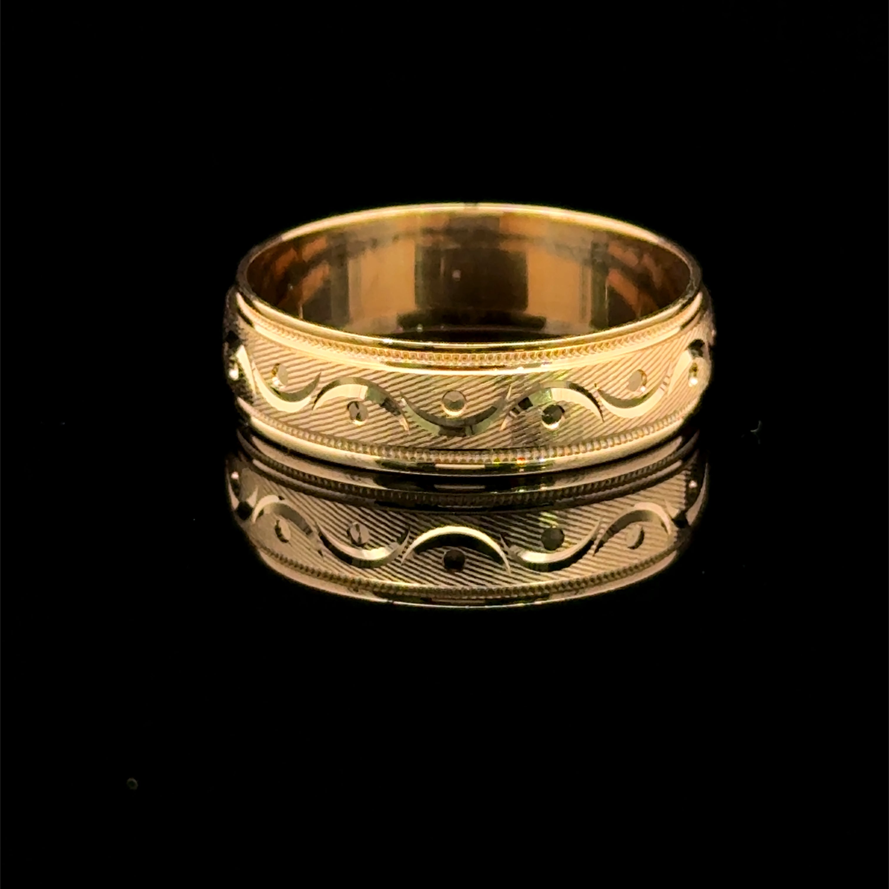 Yellow gold men’s wedding band with polished scroll pattern, circular accents, and milgrain edges available at Solomon Jeweler.