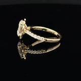 A yellow gold ring with a rectangular clear gemstone and a pavé band, shown on a reflective black surface.