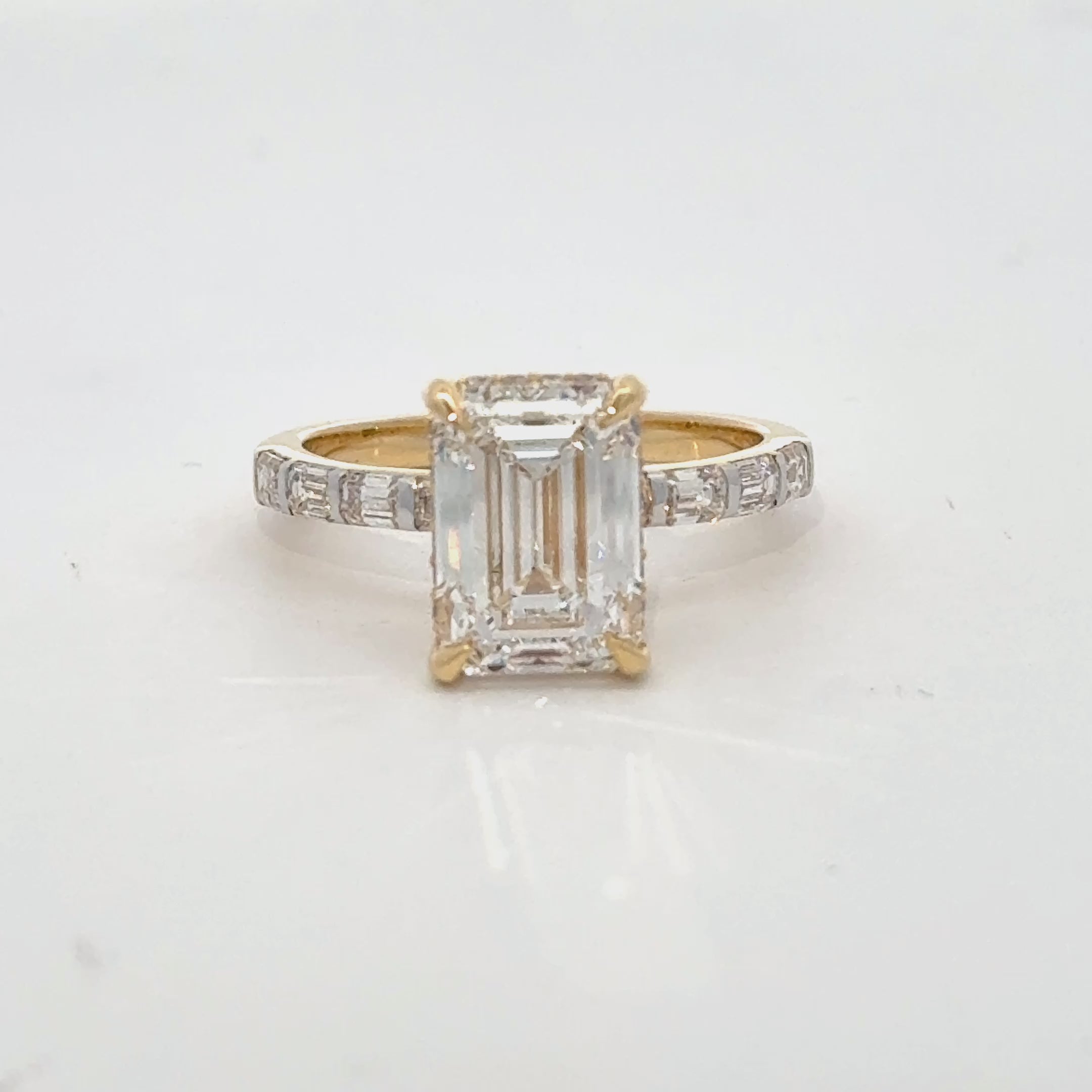 Elegant emerald-cut lab diamond ring in gold with baguette diamond shank.