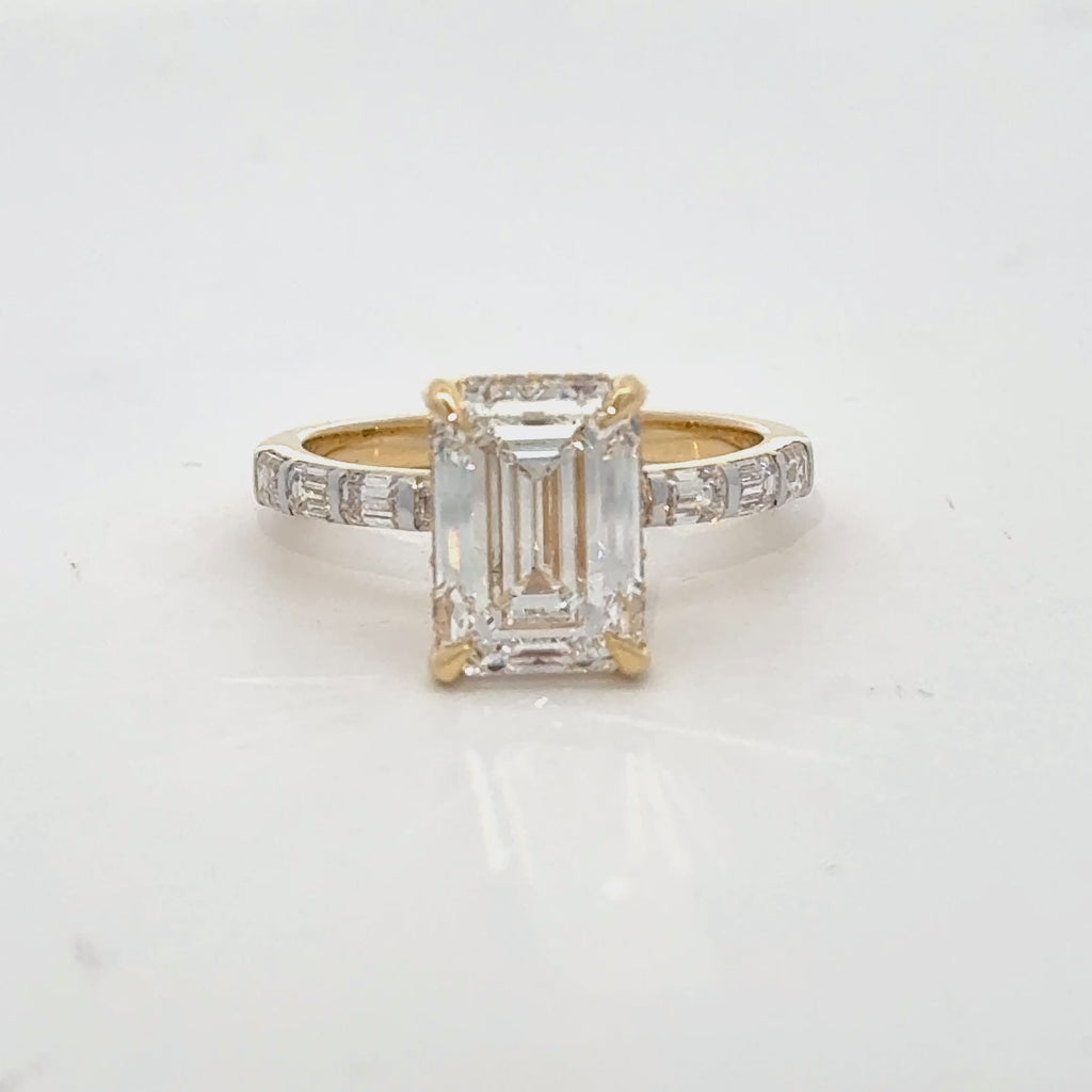 Elegant emerald-cut lab diamond ring in gold with baguette diamond shank.