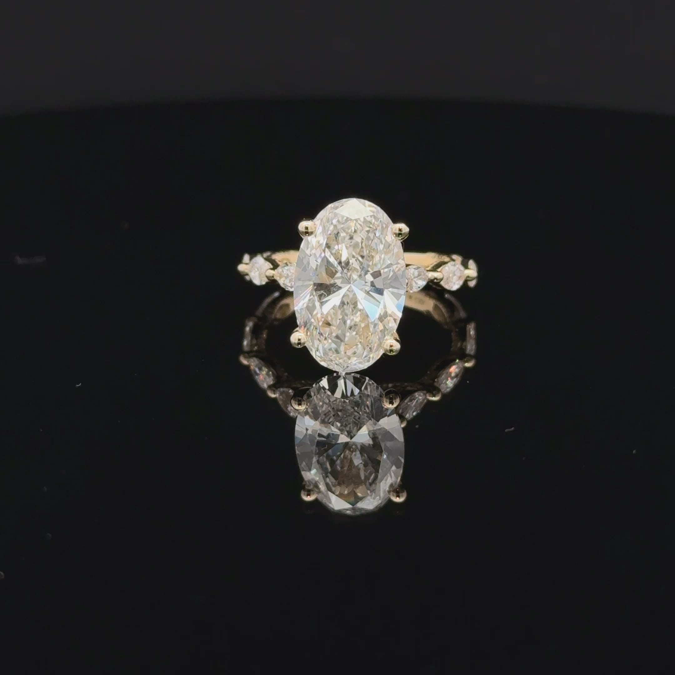 Side view of a 5 carat oval diamond ring with curved prongs, marquise-shaped band accents and beaded setting details.