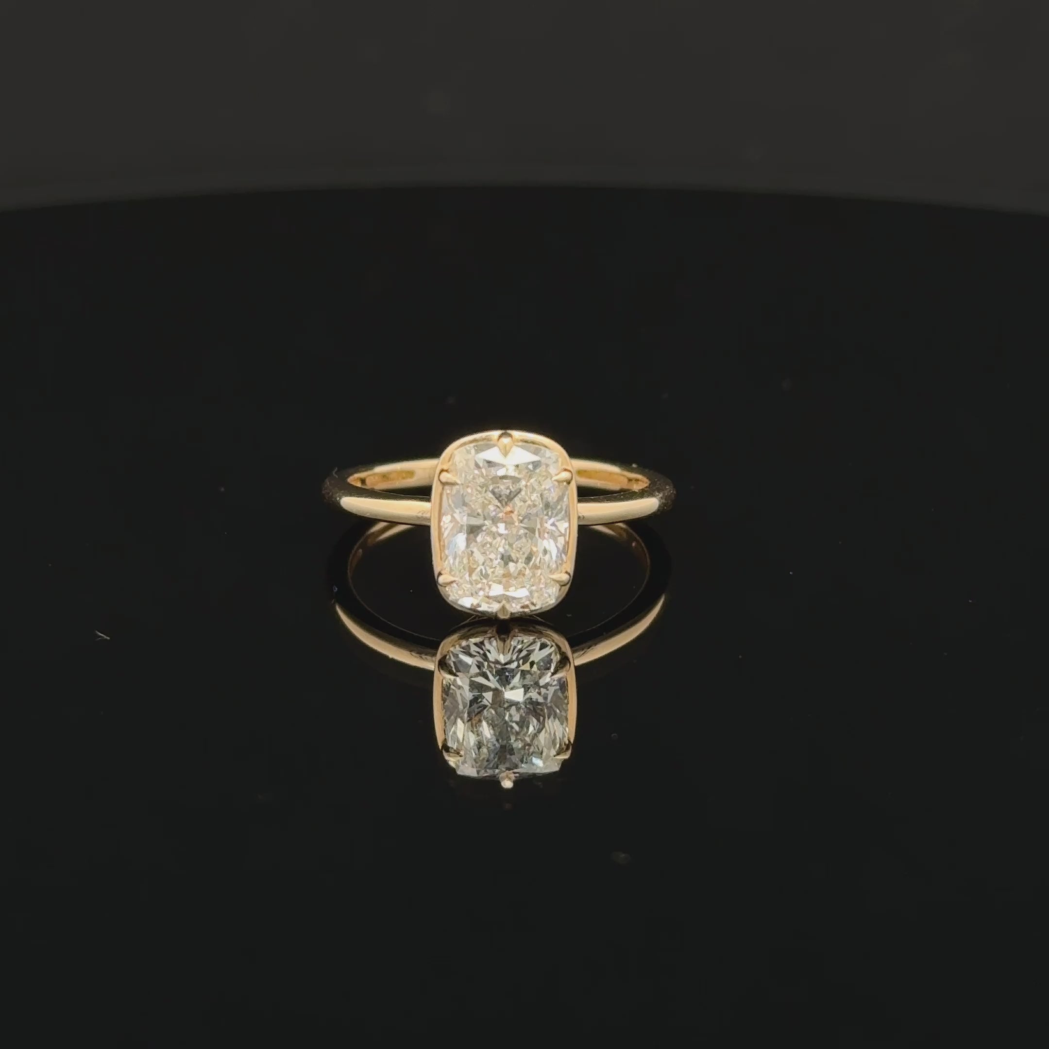 Elongated diamond solitaire ring with softly rounded corners, six prongs and a slim polished gold-toned band.