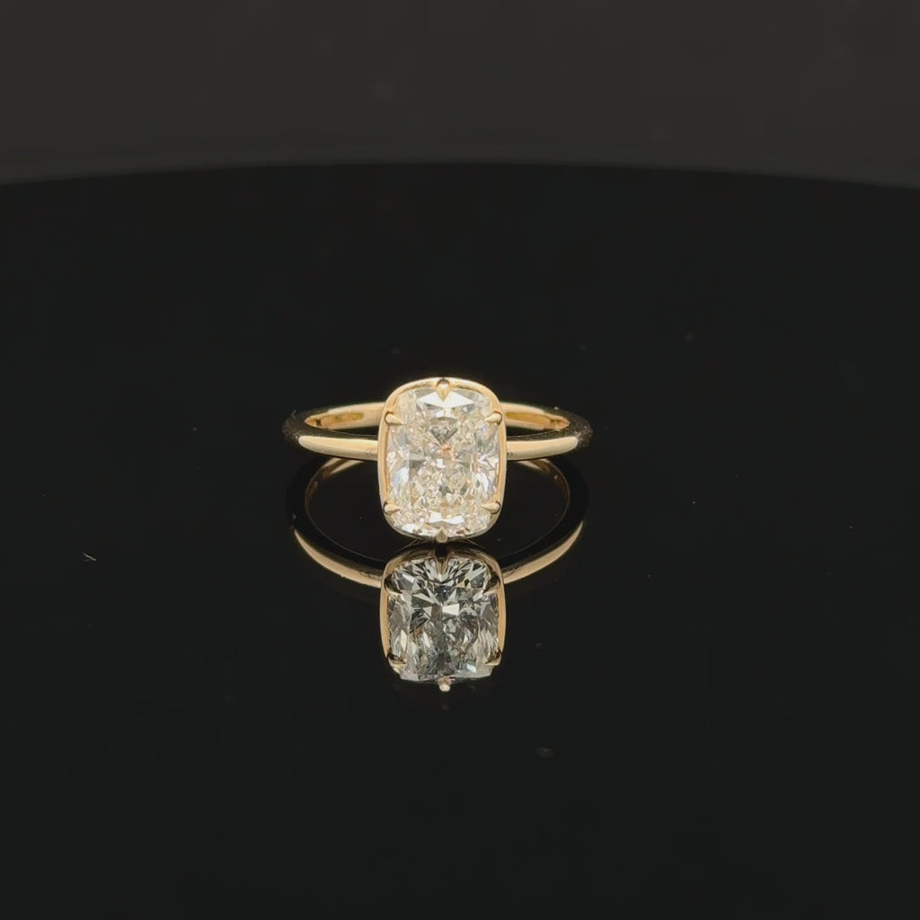 Elongated diamond solitaire ring with softly rounded corners, six prongs and a slim polished gold-toned band.