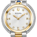 A Bulova two-tone stainless steel and yellow gold watch with a white dial, crystal-encrusted bezel, and a blue cabochon on the crown.