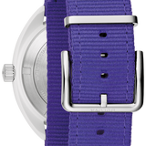 Close-up of a watch with a purple woven nylon strap and a silver-toned metal case and buckle, shown against a white background.