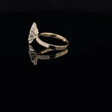 A yellow gold ring with a large triangular clear gemstone and smaller accent stones along the band, displayed on a reflective black surface.