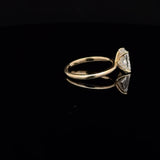 A yellow gold ring with a large clear marquise-cut gemstone in a prong setting, displayed on a reflective black surface.