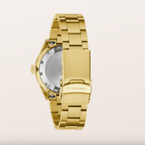 Gold-tone metal watch band and case back shown from the rear, with the brand name CARAVELLE engraved on the clasp, set against a solid off-white background.