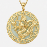 A gold pendant necklace featuring a raised dragon motif over a pale green inlay, surrounded by a decorative gold border, shown on a light gray background.